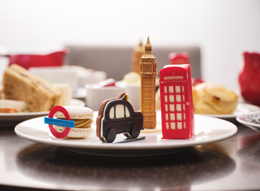 Themed afternoon teas London: a plate containing pastries and cakes shaped like Big Ben, a black cab, a red phone box and a tube roundel.